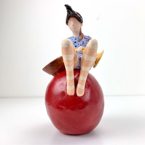 CARRIANNE L HENDRICKSON woman with beak hat sitting on apple sculpture 2… - Picture 10 of 16